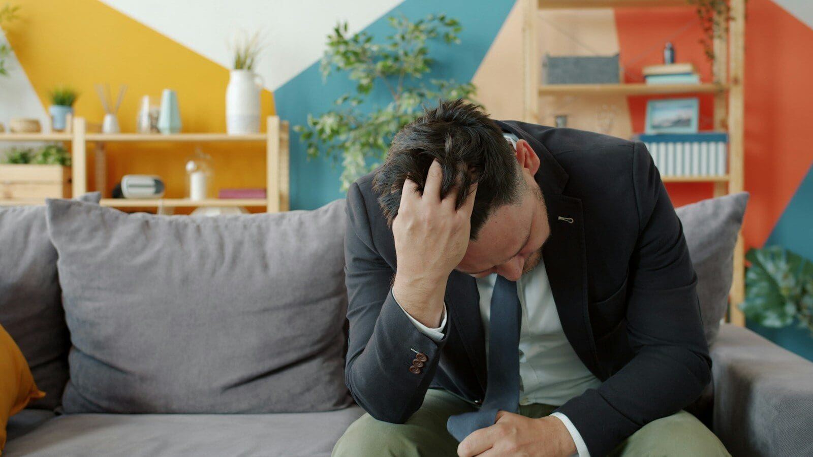 Man in suit sitting on couch with head in hands